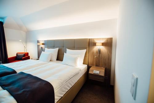 a hotel room with a large bed with white pillows at Hotel Schmachtendorf in Oberhausen
