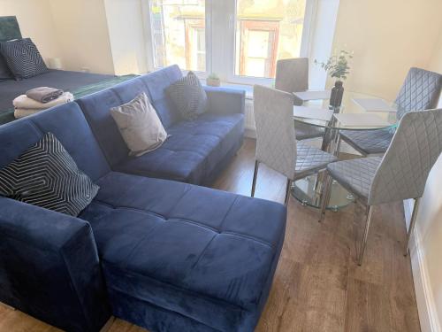 Una sala de estar con un sofá azul y una mesa. en Apartment 4- 216 high street, en Arbroath