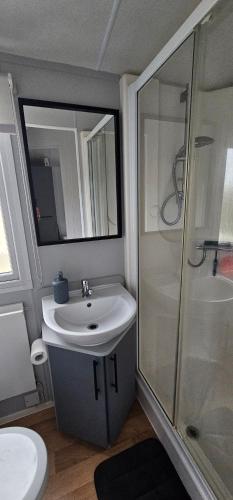een badkamer met een witte wastafel en een douche bij South Breeze Caravans Rio in Camber