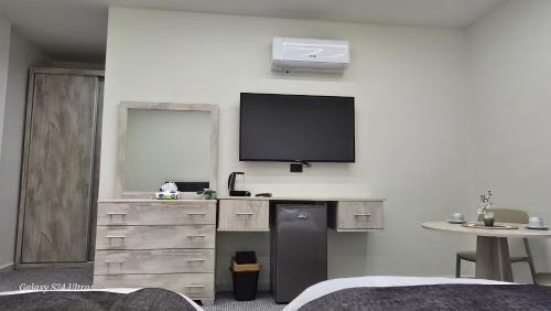 ein Schlafzimmer mit einem Fernseher an der Wand und einer Kommode in der Unterkunft Jeeso Hotel in Gerasa