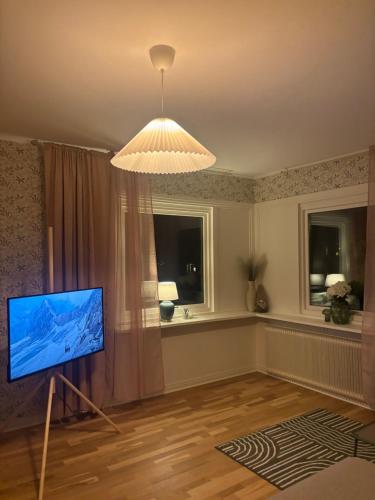 een woonkamer met een televisie en een kroonluchter bij Cozy apartment in Åmål