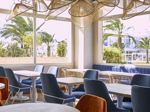 a restaurant with tables and chairs and windows at Ibis Elche in Elche