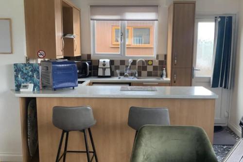 a kitchen with a counter and two chairs in it at 2 Bed Chalet Sleeps 6 - Pets Near Beach Parking in Mablethorpe