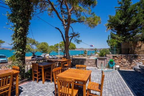a patio with tables and chairs and a view of the water at Sefa Çamlı Palas in Ayvalık