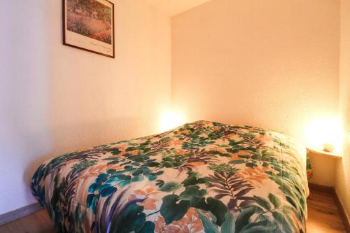 a bedroom with a bed with a flowered blanket at Studio cabine lumineux et calme, au centre de Flaine Foret in Flaine
