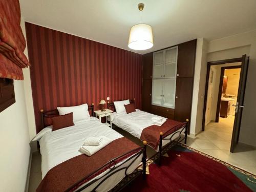 a bedroom with two beds and a red wall at Traditional Memories 2 in Tríkala