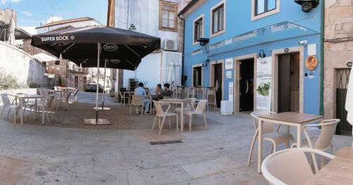 an outdoor cafe with tables and chairs and an umbrella at Blue House Ponte de Lima in Ponte de Lima