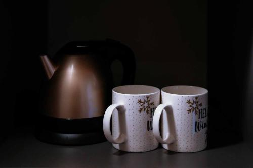 two coffee cups sitting on a table next to a tea kettle at Blue House Ponte de Lima in Ponte de Lima