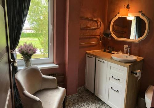 a bathroom with a chair and a sink and a window at Li Amber Apartment Carnikava in Carnikava