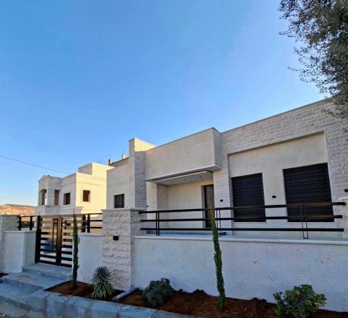 een groot wit huis met een hek ervoor bij Jeeso hotel in Jerash