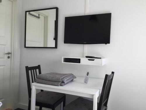 a white table with a television on a wall at Close But Quiet in Herlev