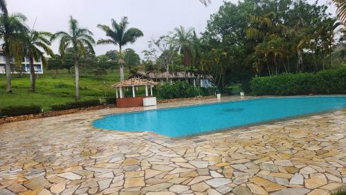 a swimming pool with a stone walkway next to a house at Quinta das Águas Hotel in Itapira