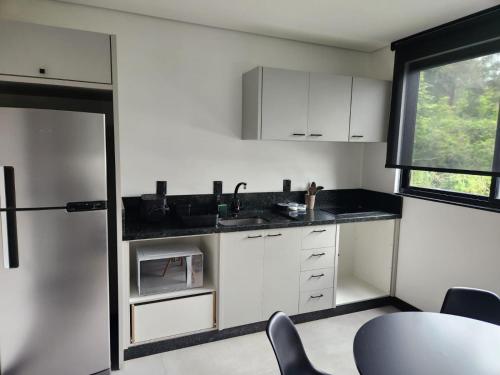 a kitchen with white cabinets and a sink and a window at Loft 06 Vila Germânica Oktoberfest Blumenau in Blumenau