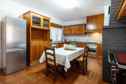 a kitchen with a table and a stainless steel refrigerator at Casa Das Fontes Ponte de Lima - Jaccuzzi and Pool in Ponte de Lima