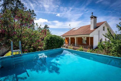 a house with a swimming pool next to a church at Casa Das Fontes Ponte de Lima - Jaccuzzi and Pool in Ponte de Lima