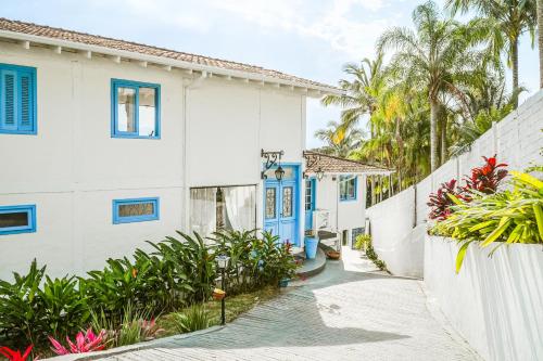 uma rua em frente a um prédio branco com portas azuis em VELINN Pousada Casa da Imperatriz em Ilhabela