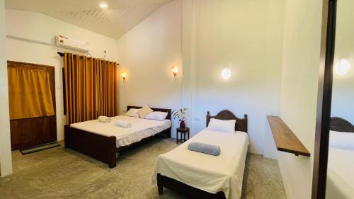 una stanza con due letti e una finestra di Unakuruwa Ravenala Homestay a Tangalle