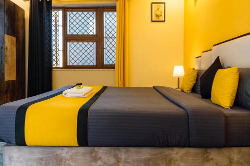 a bedroom with a large bed with yellow walls at Hidden Leaf in Dehradun