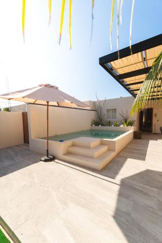 un patio avec un parasol et une piscine dans l'établissement Casa Manglar Sisal by WoWay Experiences, à Sisal
