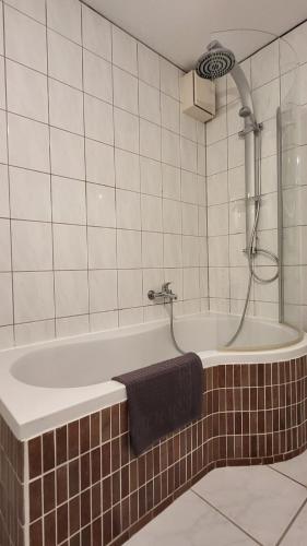 a bathroom with a tub with a shower and a towel at Deluxe Apartment Waldbröl in Waldbröl