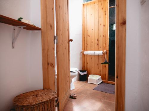 a bathroom with a toilet and a wooden door at Casita - your home in Flores in Lajes das Flores