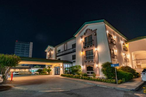 ein großes weißes Gebäude mit Parkplatz bei Nacht in der Unterkunft Quinta Dorada Hotel & Suites in Saltillo
