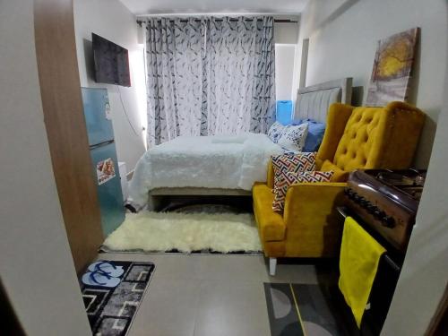 a bedroom with a bed and a yellow chair at Akb Home Nyayo Studio in Nairobi