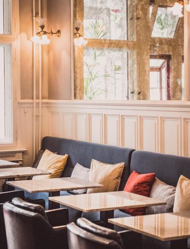 a room with tables and couches and a window at HENRI Hotel Berlin Kurfürstendamm in Berlin