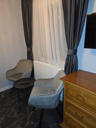 two chairs and a dresser in a room with a window at Bârlogul balaurului in Afumaţi