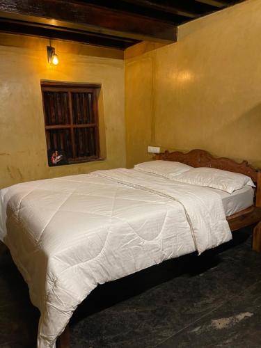 a bedroom with a large bed with white sheets at Aravanazhi tharavadu in Thirunelli