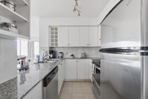a white kitchen with a sink and a refrigerator at Stylish 2BR Downtown Escape Prime Victoria Spot in Toronto