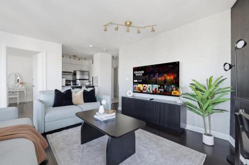 a living room with a couch and a tv on a wall at Stylish 2BR Downtown Escape Prime Victoria Spot in Toronto