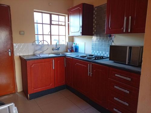 una cucina con mobili rossi e un piano di lavoro nero di LeGae Apartments a Gaborone