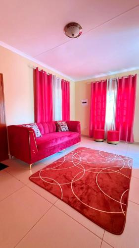 un soggiorno con un divano rosso e tende rosse di LeGae Apartments a Gaborone
