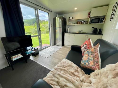 a living room with a couch and a large window at Ongarue Cottage in Ongarue
