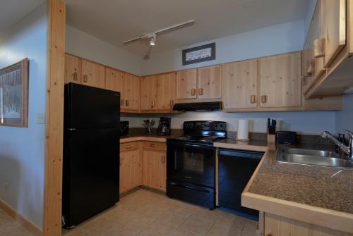 a kitchen with wooden cabinets and a black refrigerator at The Way Home at Tensleep North in Teton Village