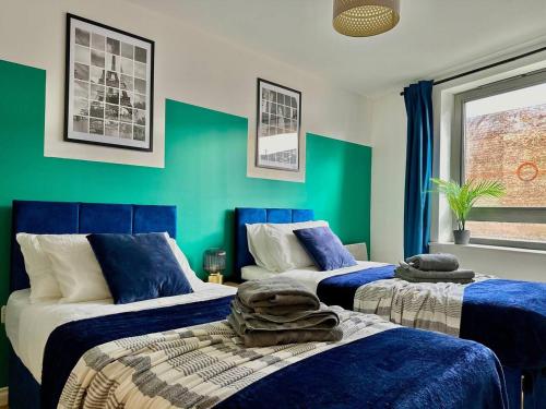 1 Schlafzimmer mit 2 Betten mit blauen und grünen Wänden in der Unterkunft Watford Serviced Apartment, Free Parking, City Centre Sleeps 5 in Watford