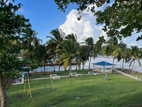 a park next to the water with swings and trees at Oceanfront Oasis - Panoramic Views & Marina Access in Beltran