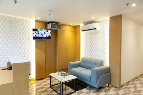 a waiting room with a blue chair and a table at Hotel Stayzi Inn in Navi Mumbai