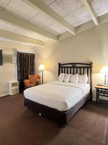 a bedroom with a large bed and a chair at Windjammer Lodge in Ogdensburg