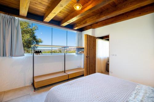 a bedroom with a bed and a large window at Villa Sole Tra i Ginepri in Olbia
