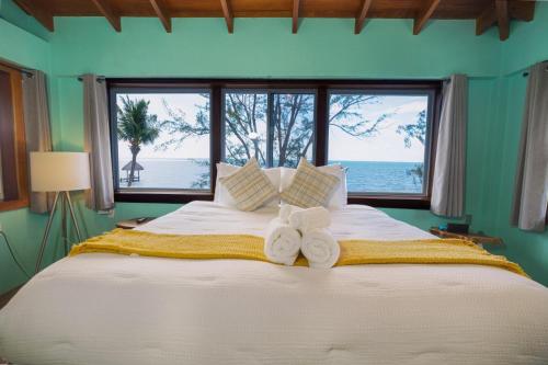 a bedroom with a large bed with towels on it at Toucan Dance Villa - 3BR Beachfront wPool Ocean Views in Maya Beach