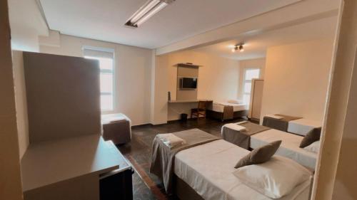 a hotel room with two beds and a desk at Trade Hotel Diadema in Diadema