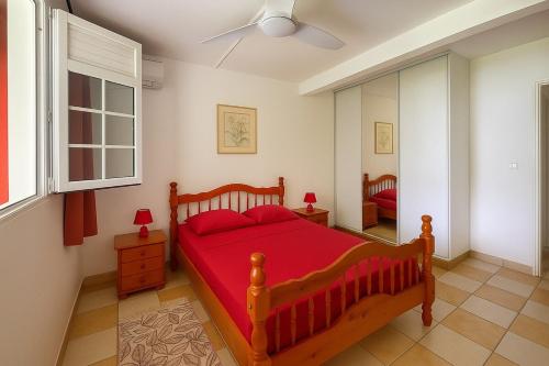 een slaapkamer met een rood bed en een raam bij T2 Tropical avec terrasse et jardin in La Trinité