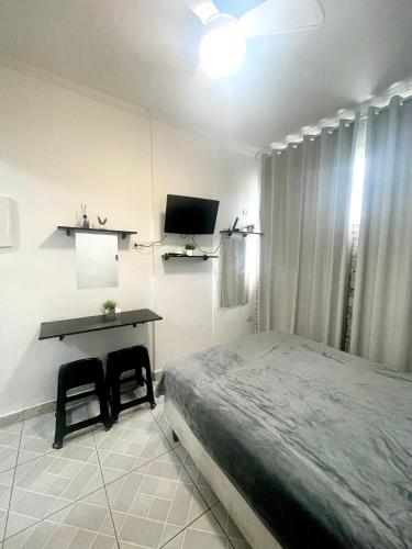 um quarto com uma cama e uma escrivaninha com duas cadeiras em Brisa dos Sonhos em São Vicente