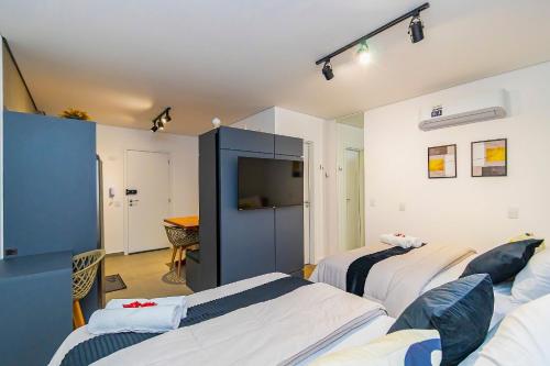 a hotel room with three beds and a tv at Studio com 2 Camas de Casal e Garagem - EIX0705 in Curitiba