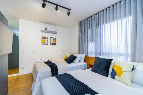 a bedroom with two beds and a window at Studio com 2 Camas de Casal e Garagem - EIX0705 in Curitiba