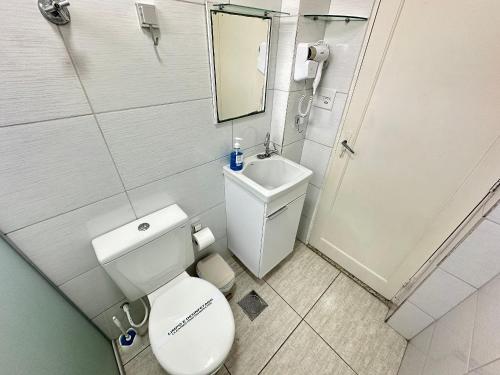 a small bathroom with a toilet and a sink at Kitnet vista Mar, pé na areia – Guilhermina in Praia Grande