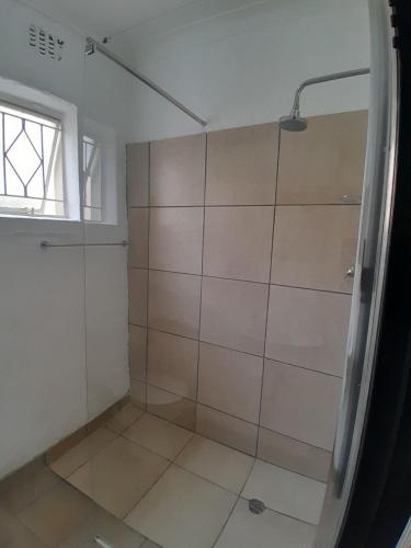 a shower with a glass door in a bathroom at Sunlit Retreat Constantia Kloof in Roodepoort