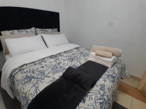 a bed with a black and white comforter and two towels at Sunlit Retreat Constantia Kloof in Roodepoort